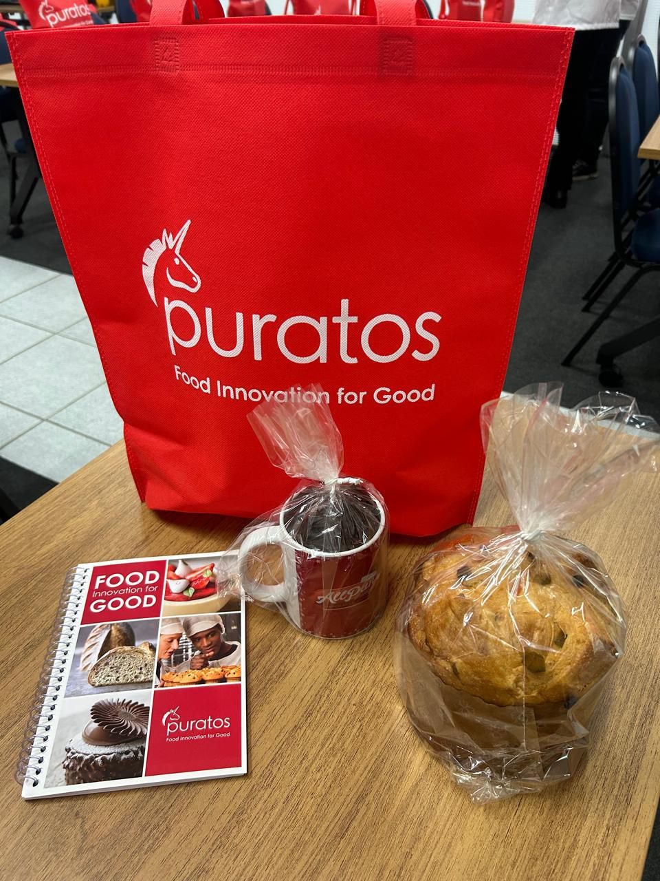 Uma bolsa vermelha da puratos fica sobre uma mesa de madeira