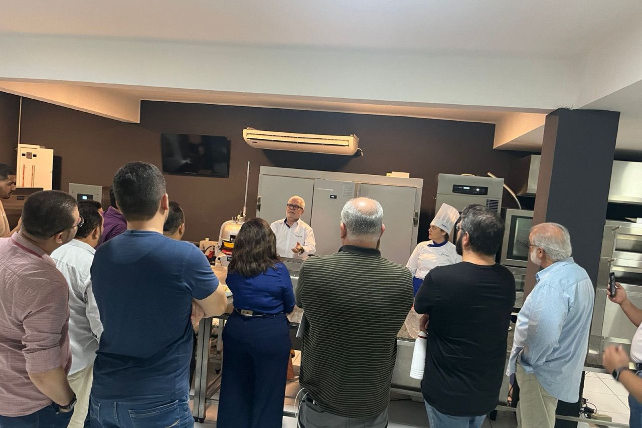 Um grupo de pessoas está em uma sala observando um chef.