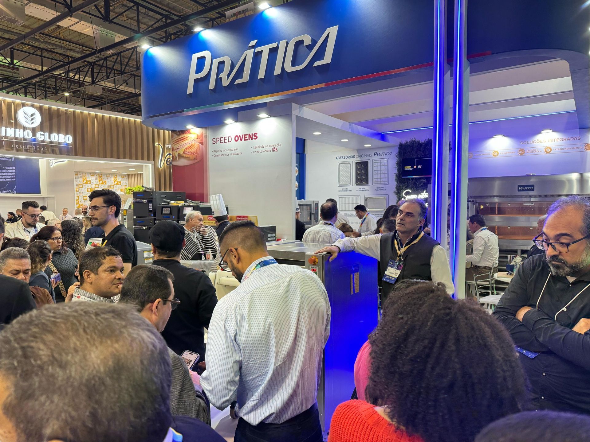 Um grupo de pessoas está em frente a um estande em uma convenção.