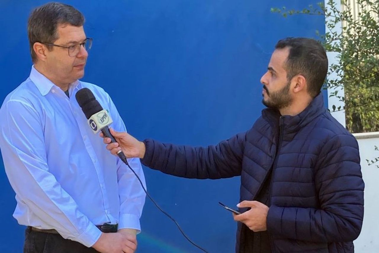 Um homem está falando em um microfone enquanto outro homem segura um telefone celular.