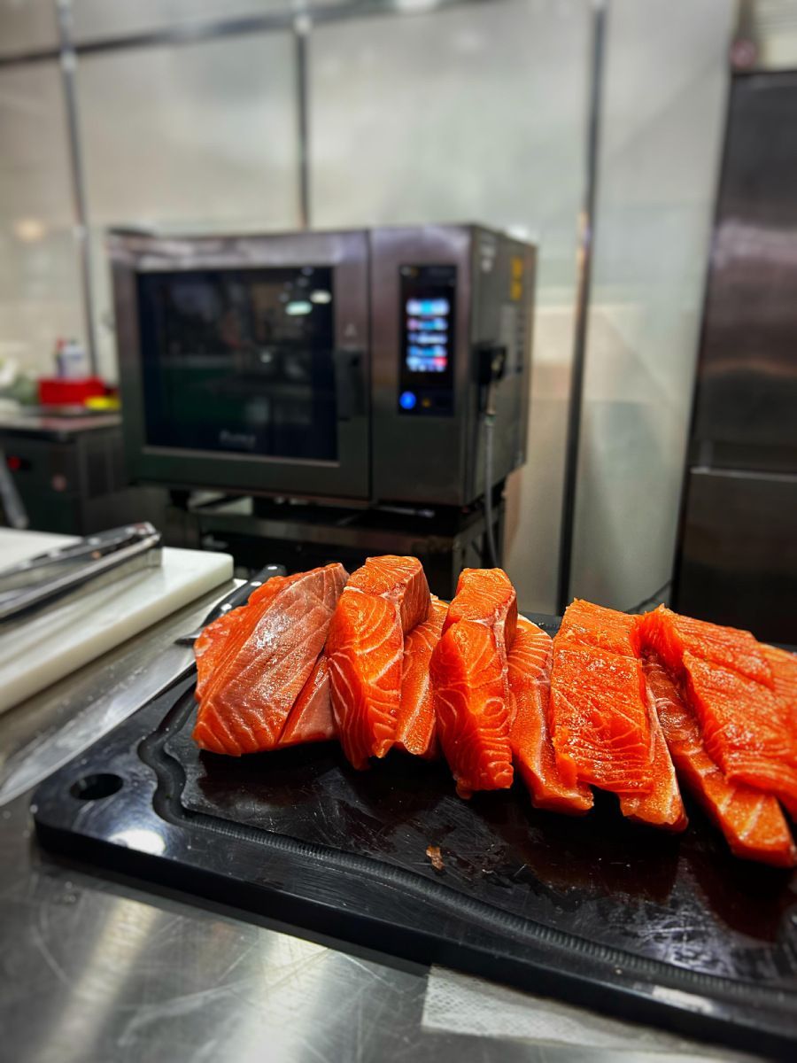 Uma tábua de corte com fatias de salmão em uma cozinha.