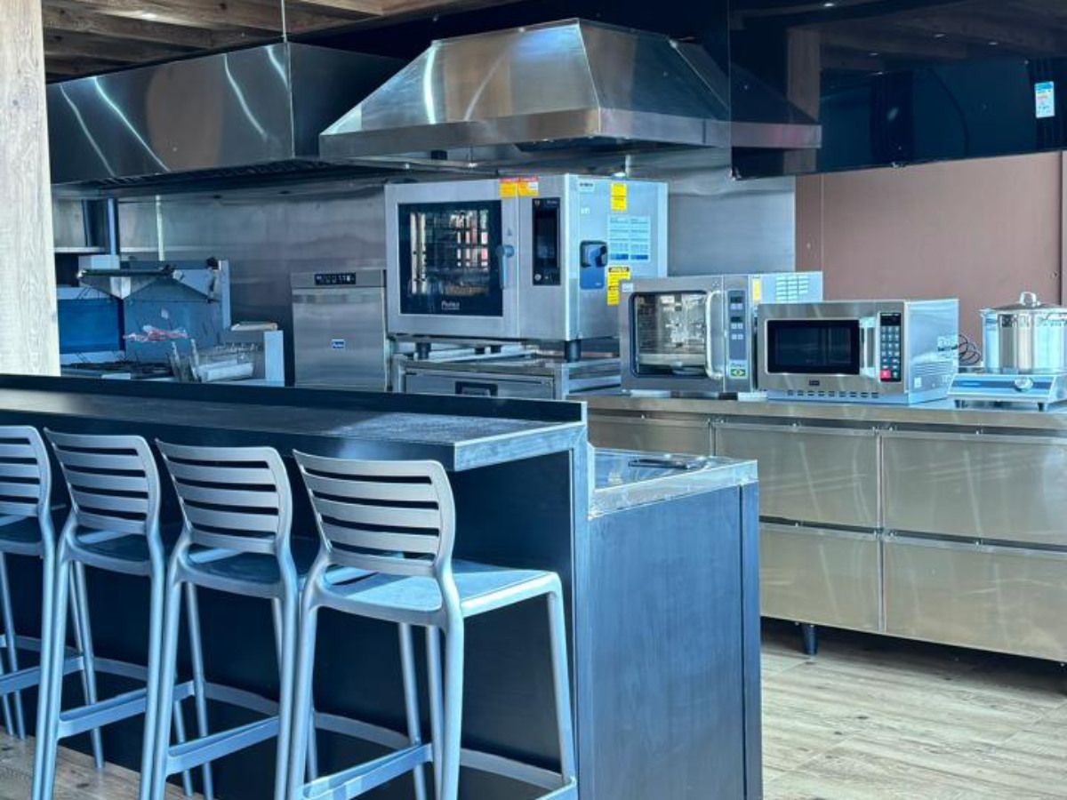 Uma cozinha com eletrodomésticos de aço inoxidável e um bar com bancos.