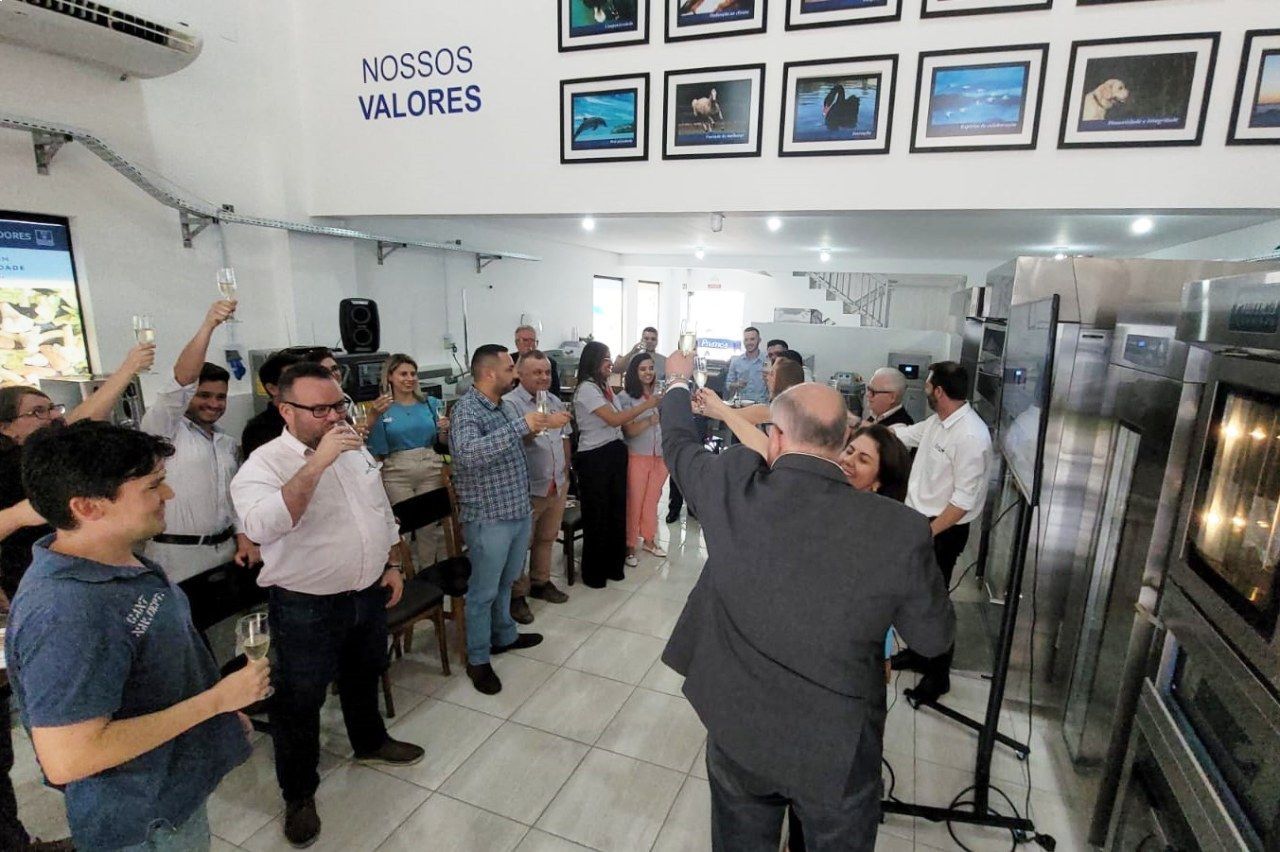 Um grupo de pessoas está em uma sala com uma placa que diz