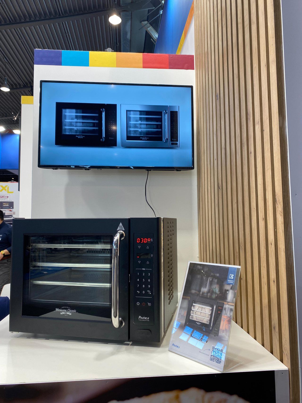 Um forno de micro-ondas está sobre uma mesa ao lado de uma TV