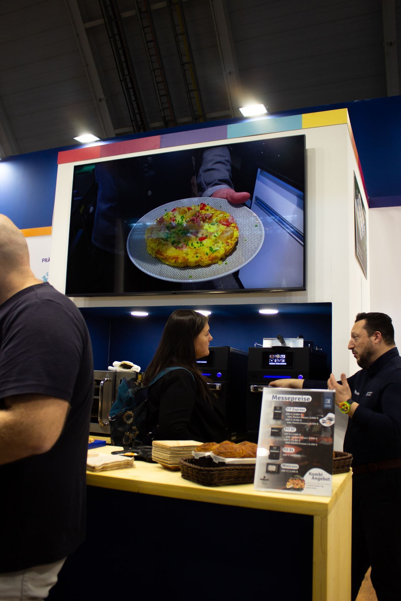 Uma mulher segura um prato de comida em frente a uma tela grande.