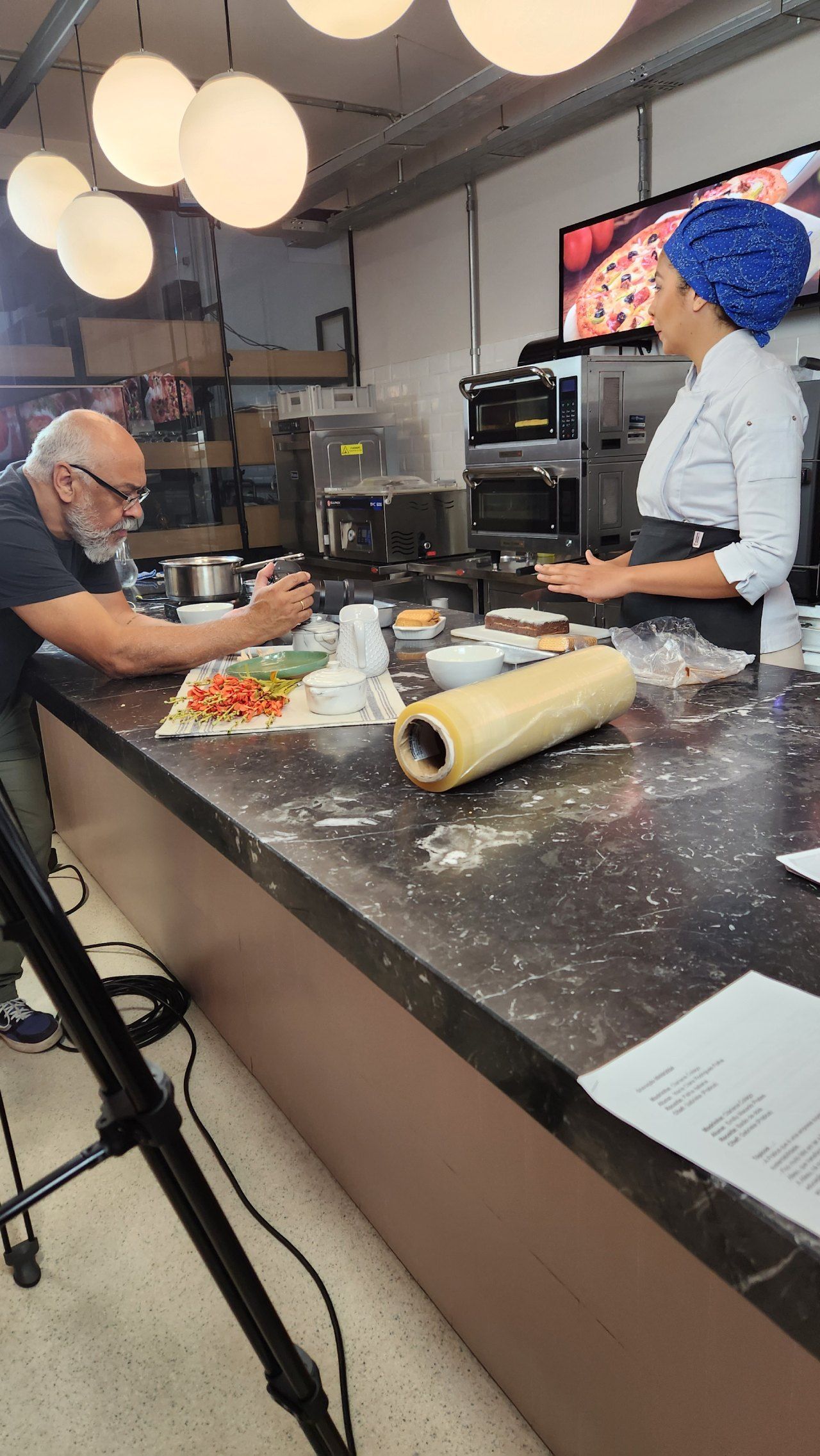 Um homem e uma mulher estão sentados em um balcão de uma cozinha preparando comida.