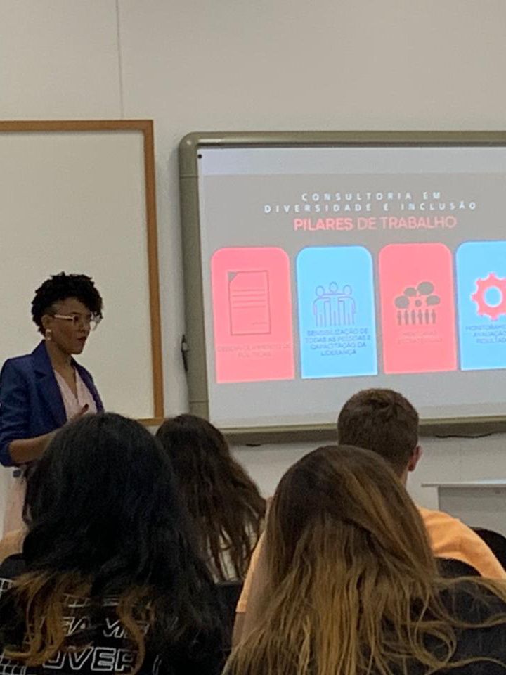 Uma mulher está fazendo uma apresentação para um grupo de pessoas em uma sala de aula.