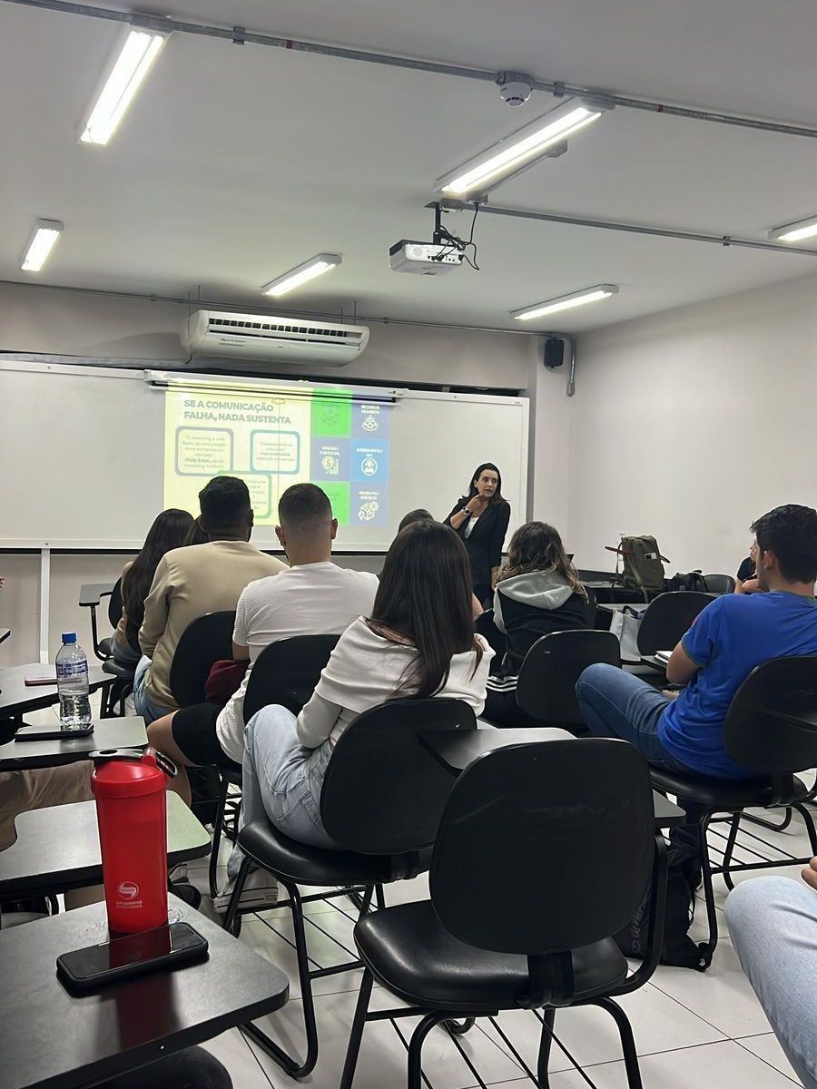 Uma mulher está fazendo uma apresentação para um grupo de pessoas em uma sala de aula.