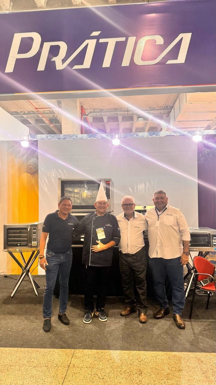 Quatro homens posam em frente a uma placa com a inscrição 