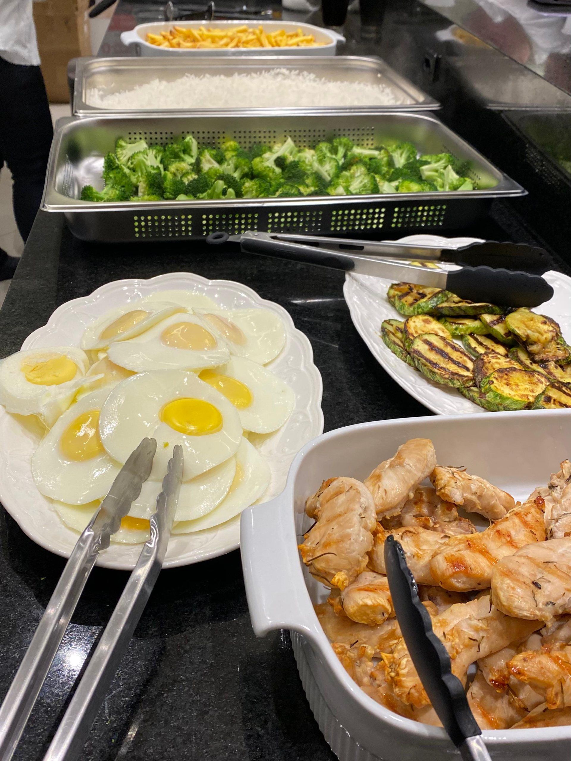 Uma mesa de bufê com ovos, brócolis e frango grelhado