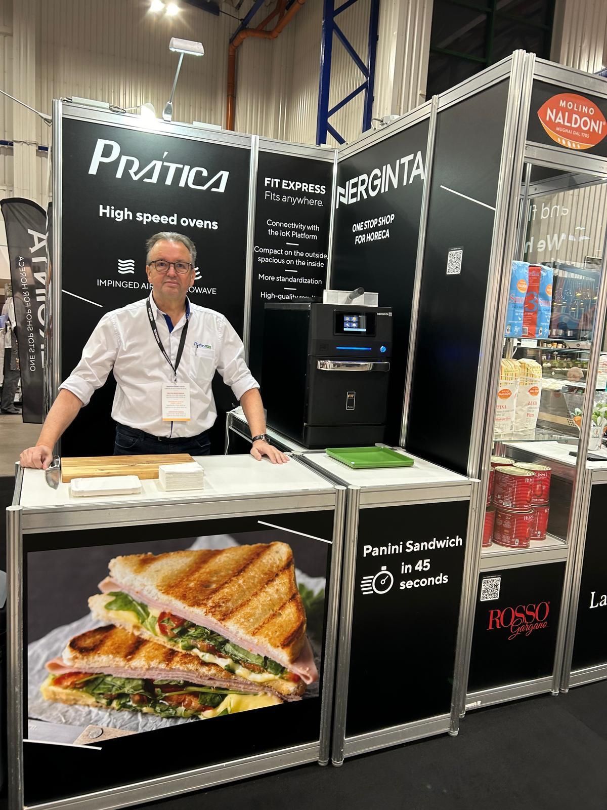 Um homem está de pé em frente a uma mesa com a imagem de um sanduíche.