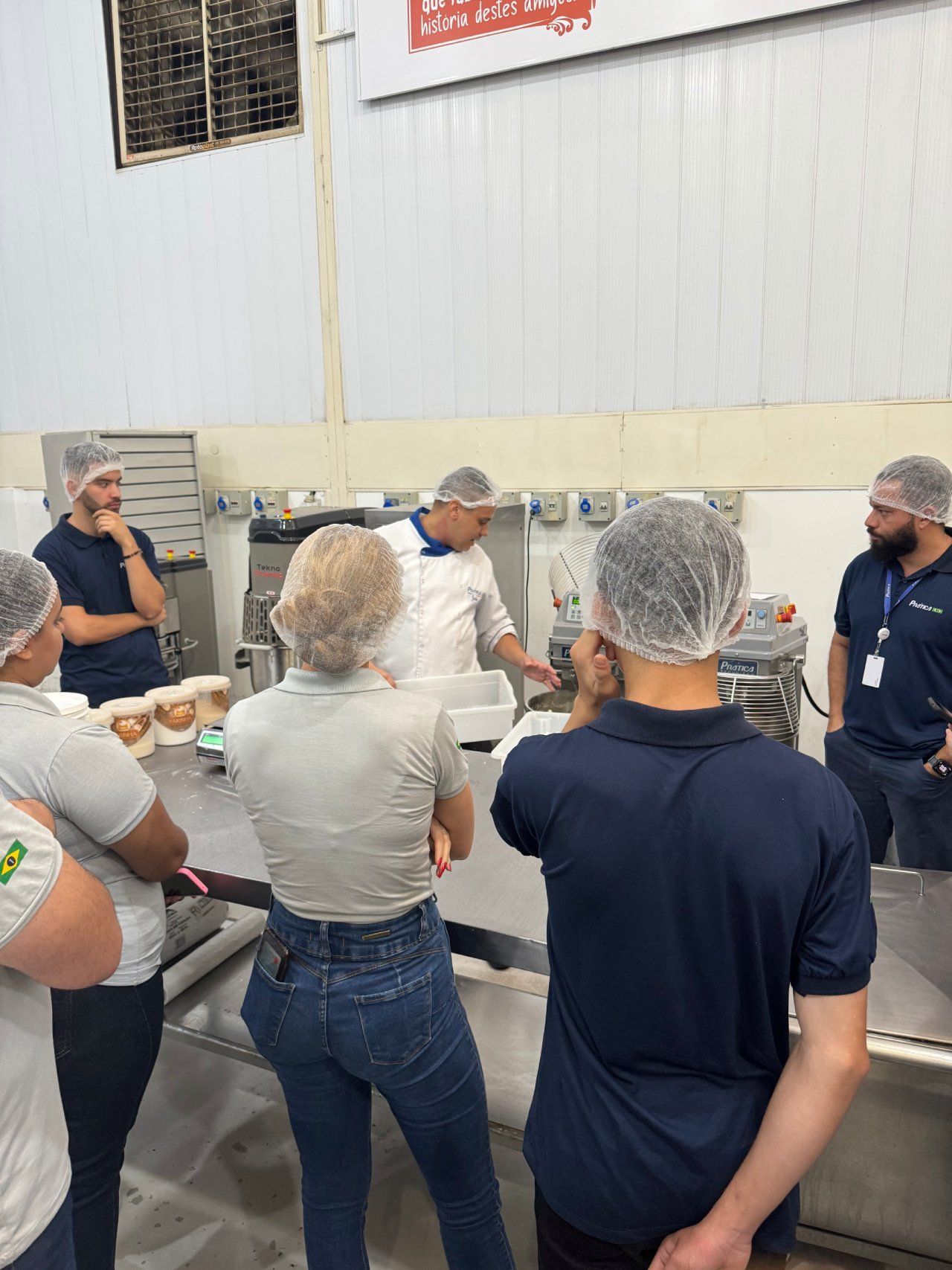 Um grupo de pessoas em pé ao redor de uma mesa em uma cozinha