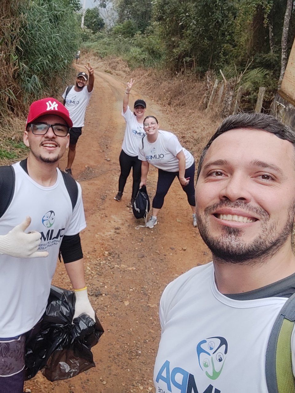 Um grupo de pessoas está em uma estrada de terra tirando uma selfie.