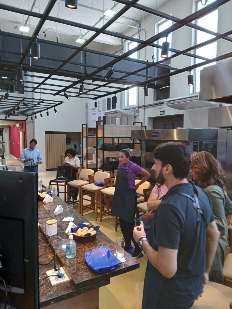 Um grupo de pessoas está em volta de uma mesa na cozinha.