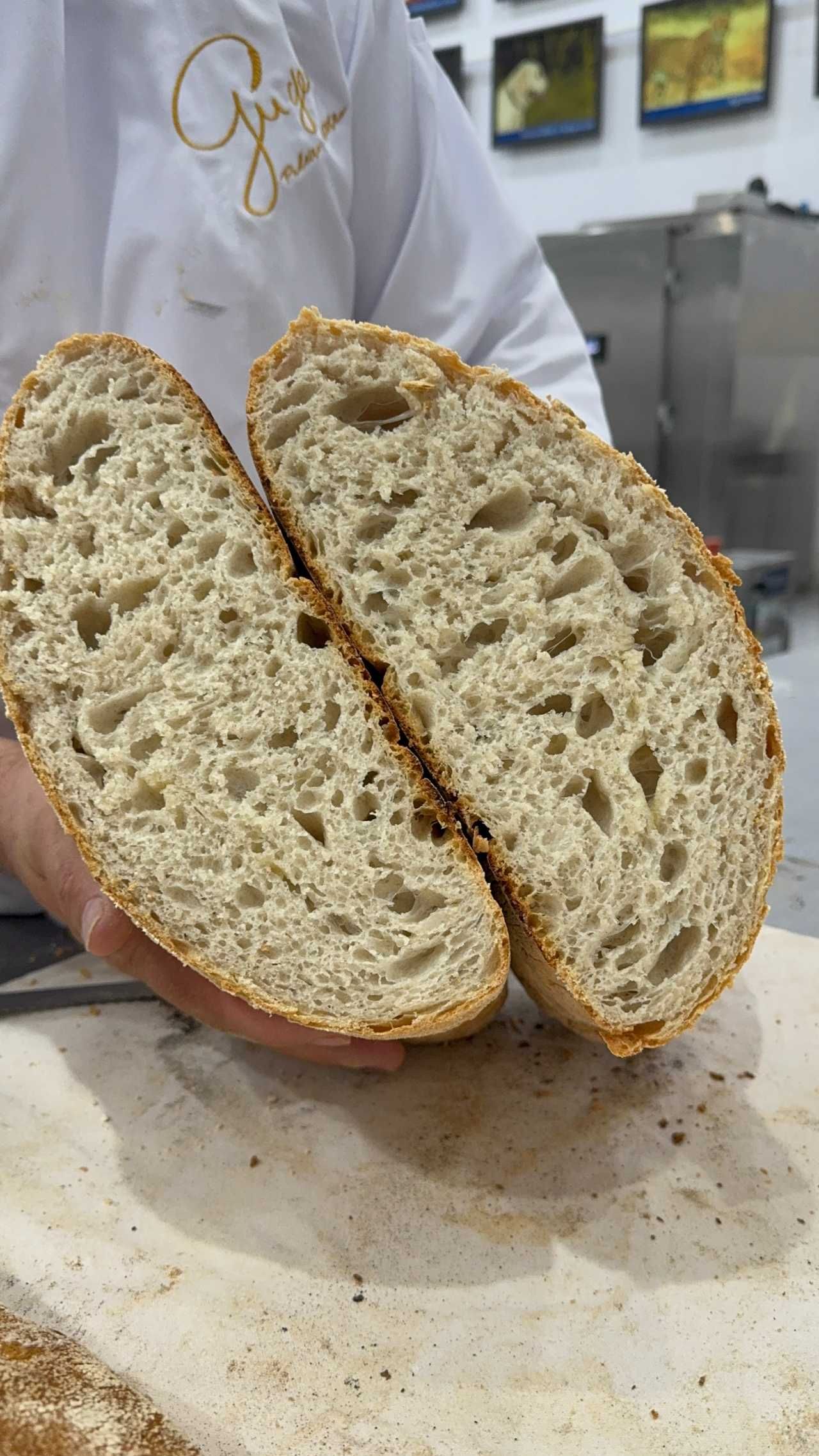 Uma pessoa está segurando um pão que foi cortado ao meio.