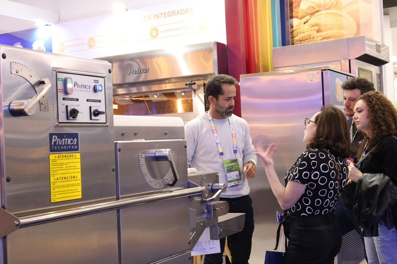 Um grupo de pessoas está em volta de uma máquina de aço inoxidável.