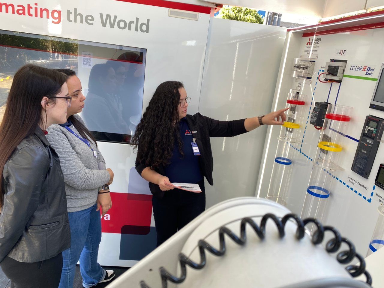 Três mulheres estão em frente a uma placa que diz 'fazendo o mundo'