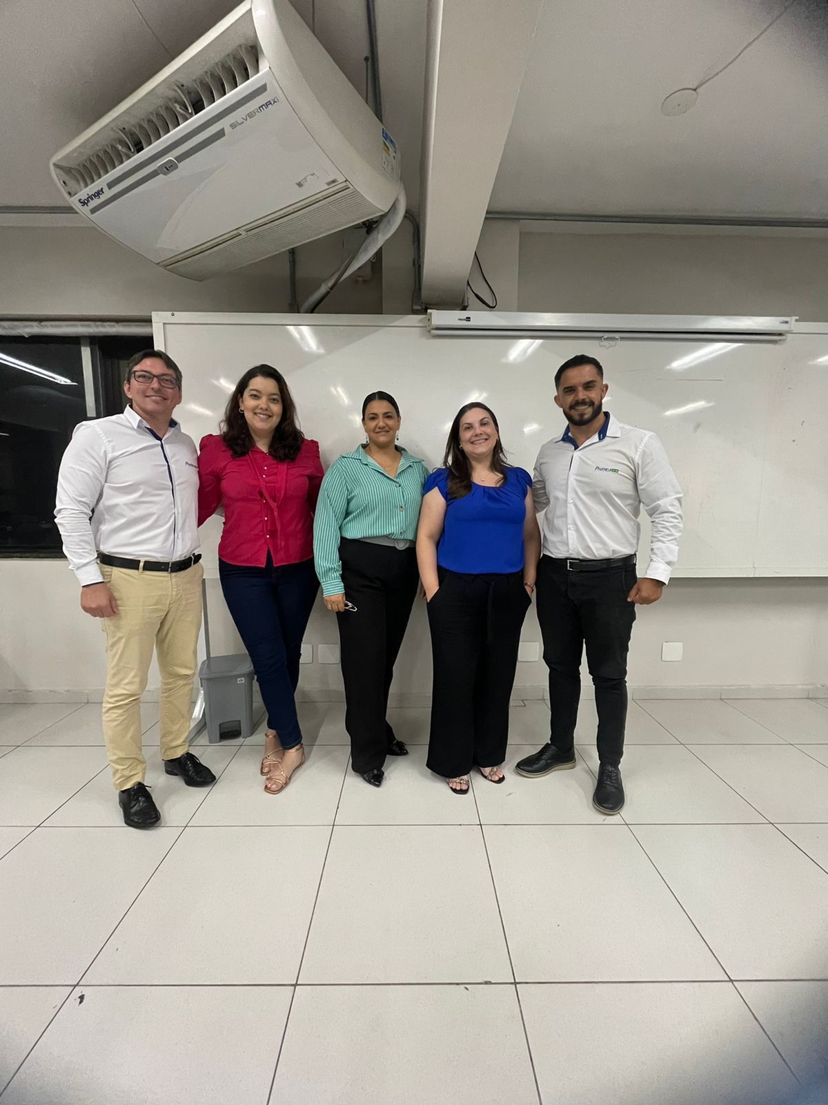 Um grupo de pessoas está posando para uma foto em uma sala.