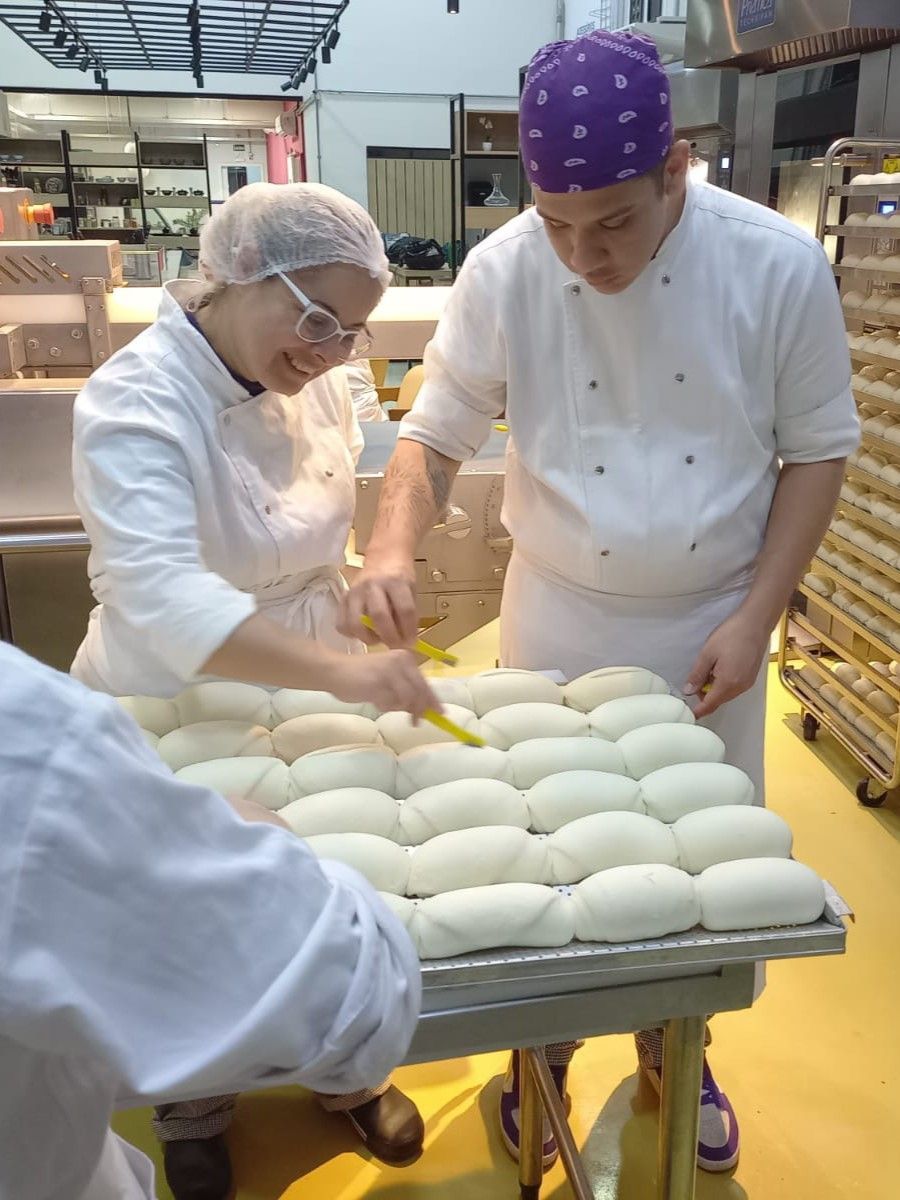 Um homem e uma mulher estão trabalhando na massa em uma padaria