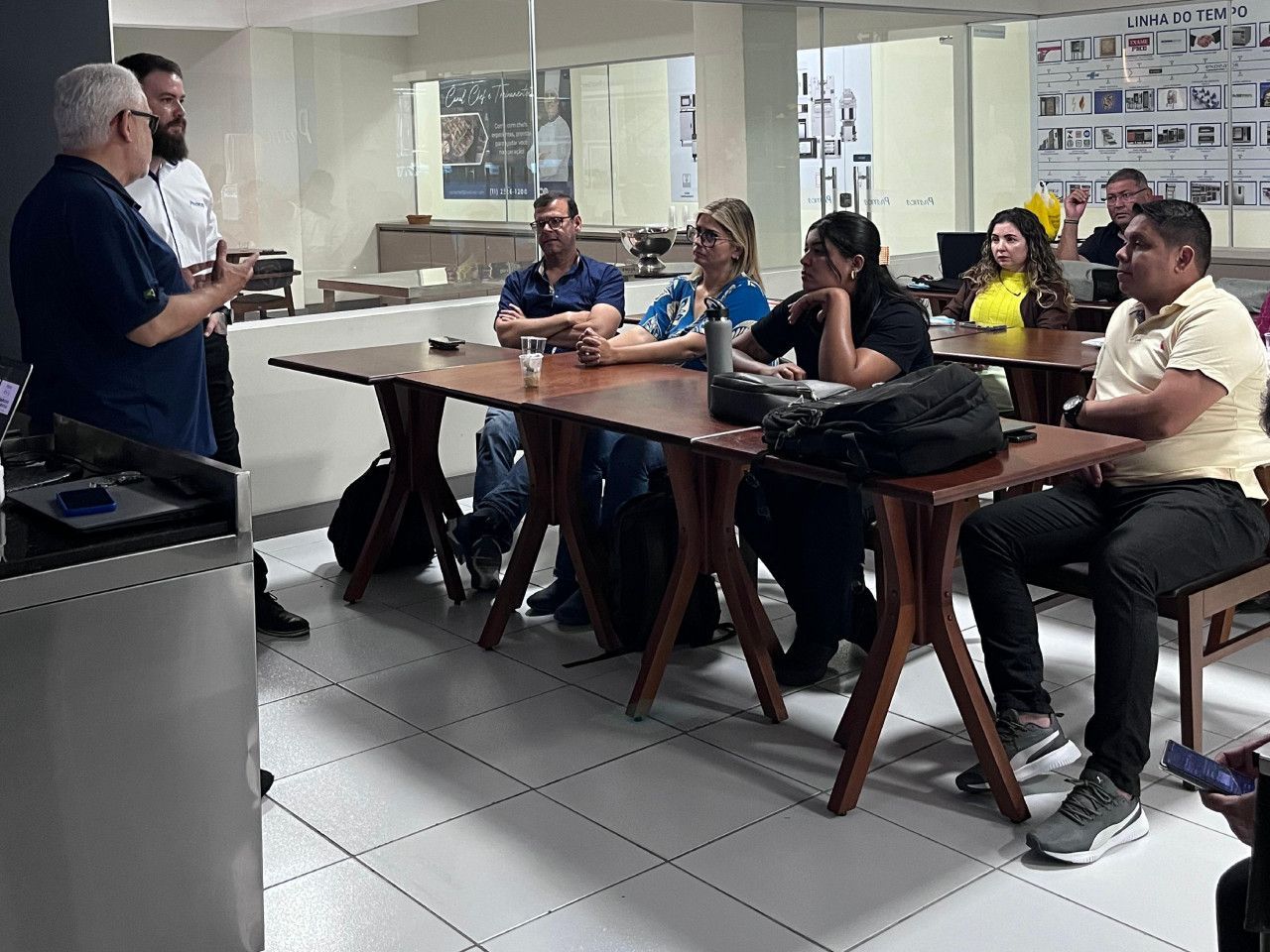Um homem está fazendo uma apresentação para um grupo de pessoas sentadas em mesas.