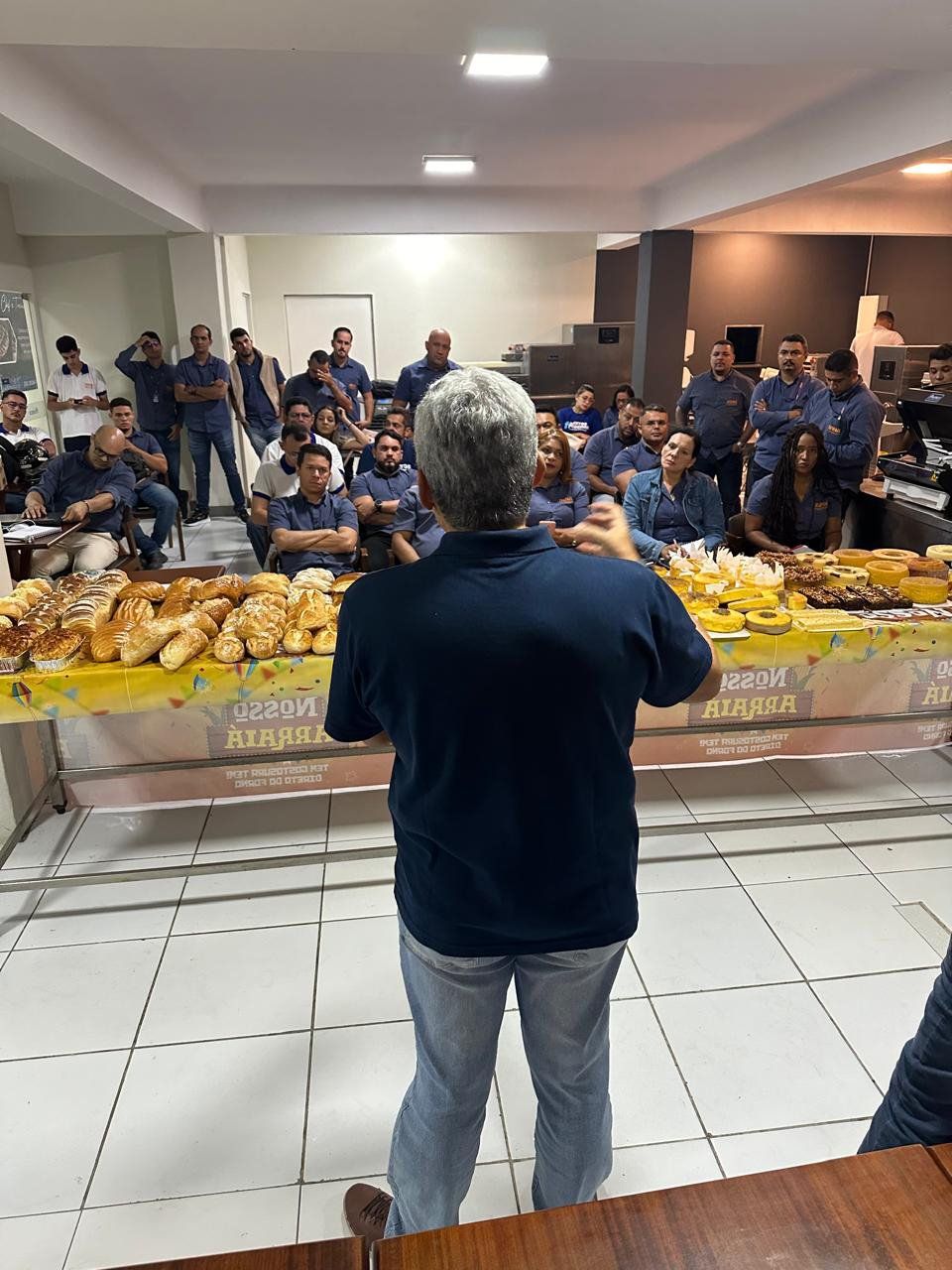 Um homem está de pé em frente a uma mesa cheia de comida.