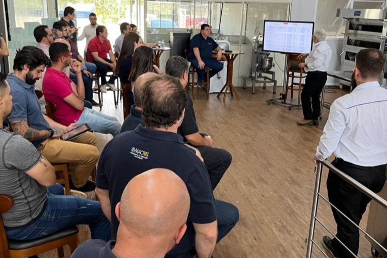 Um homem está fazendo uma apresentação para um grupo de pessoas sentadas em cadeiras.