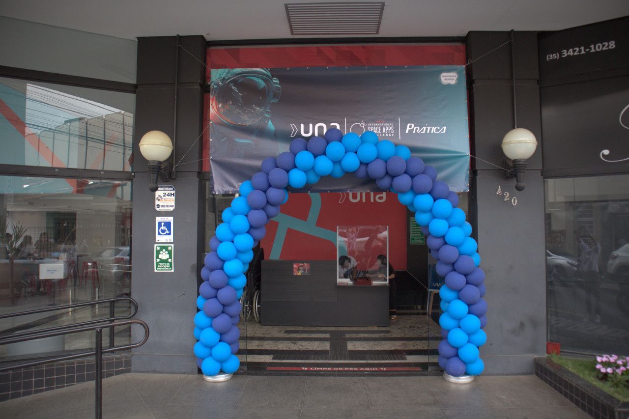 Um arco de balões azuis e roxos está em frente a um prédio.