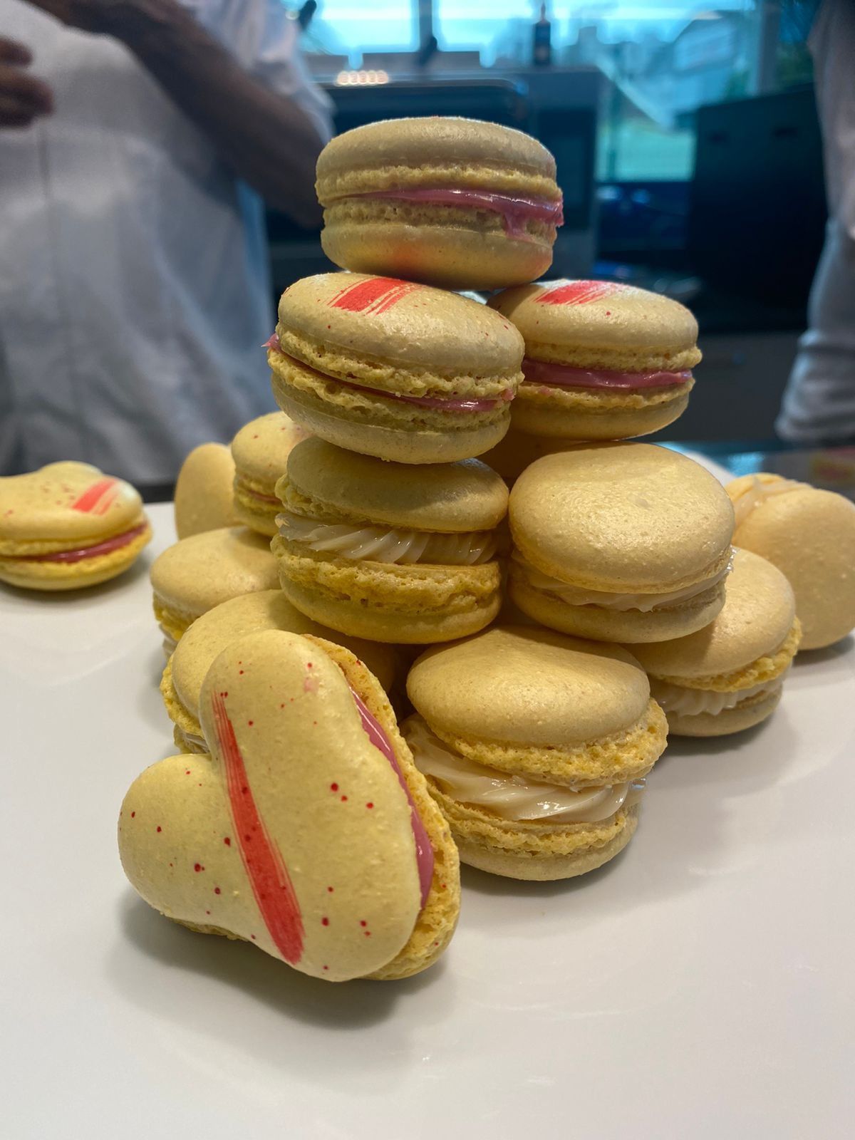 Uma pilha de macarons empilhados uns sobre os outros em um prato branco.