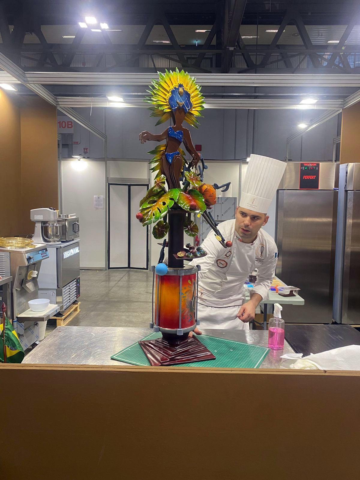 Um chef está fazendo uma escultura de chocolate em uma cozinha.