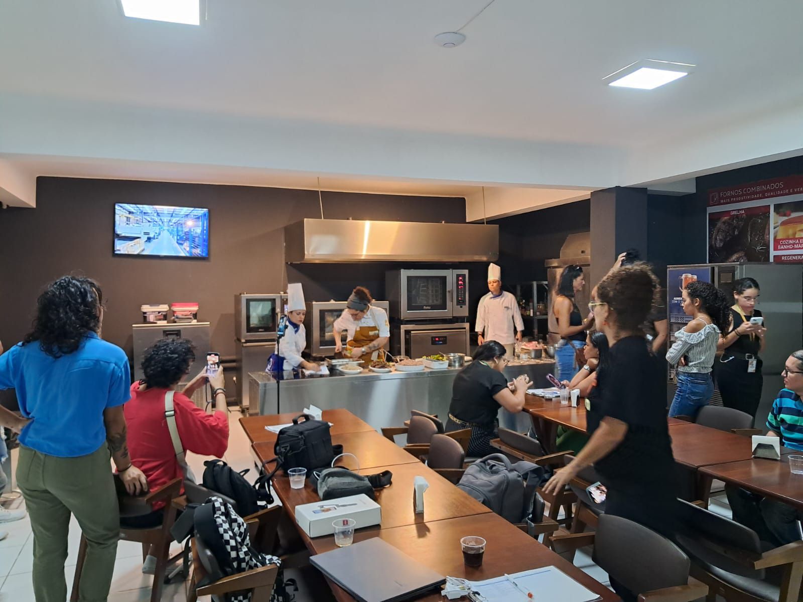 Um grupo de pessoas está de pé ao redor das mesas em um restaurante.