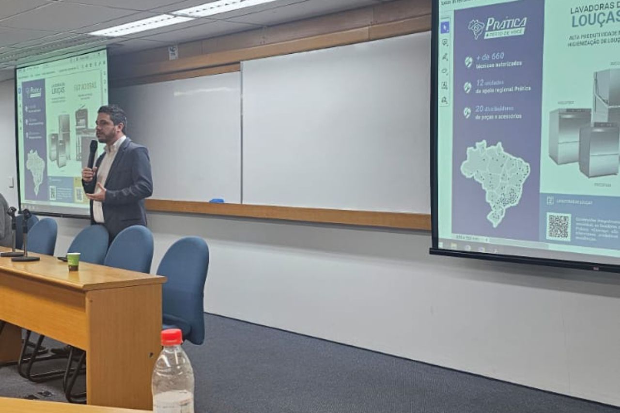 Um homem está fazendo uma apresentação em frente a uma tela grande.