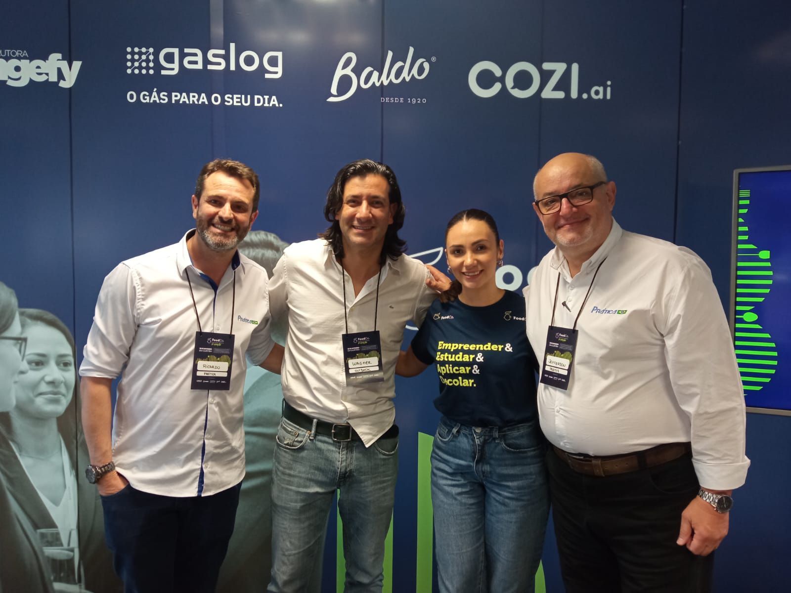 Um grupo de pessoas está posando para uma foto em frente a uma parede azul.