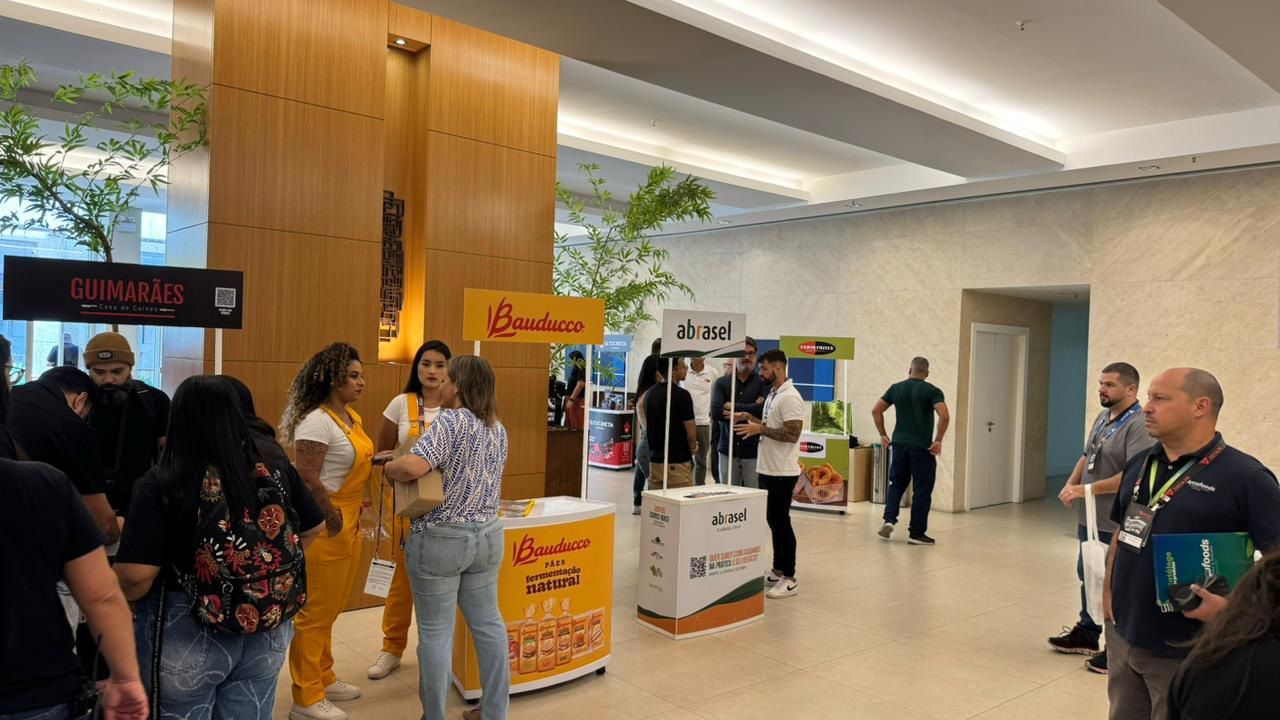 Um grupo de pessoas está de pé ao redor de mesas em uma sala.