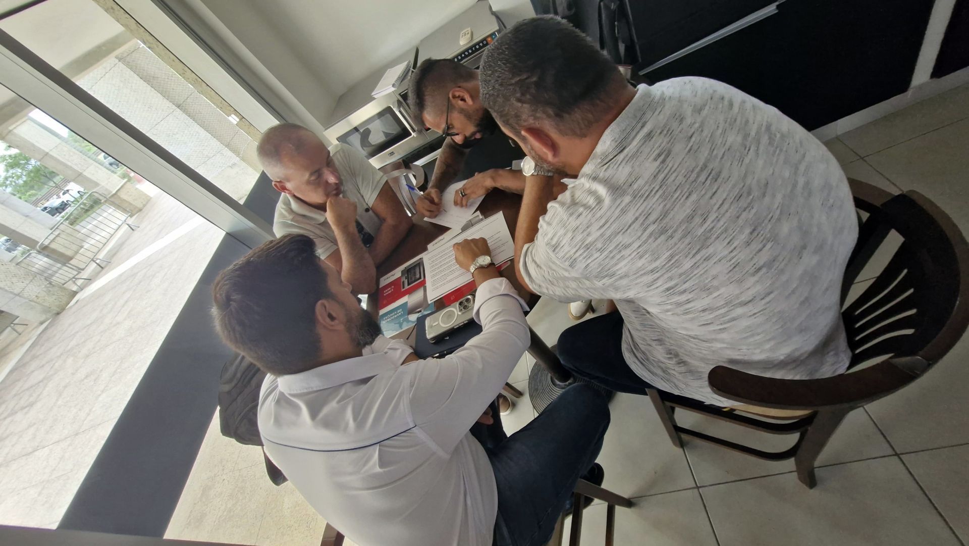 Um grupo de homens está sentado ao redor de uma mesa.