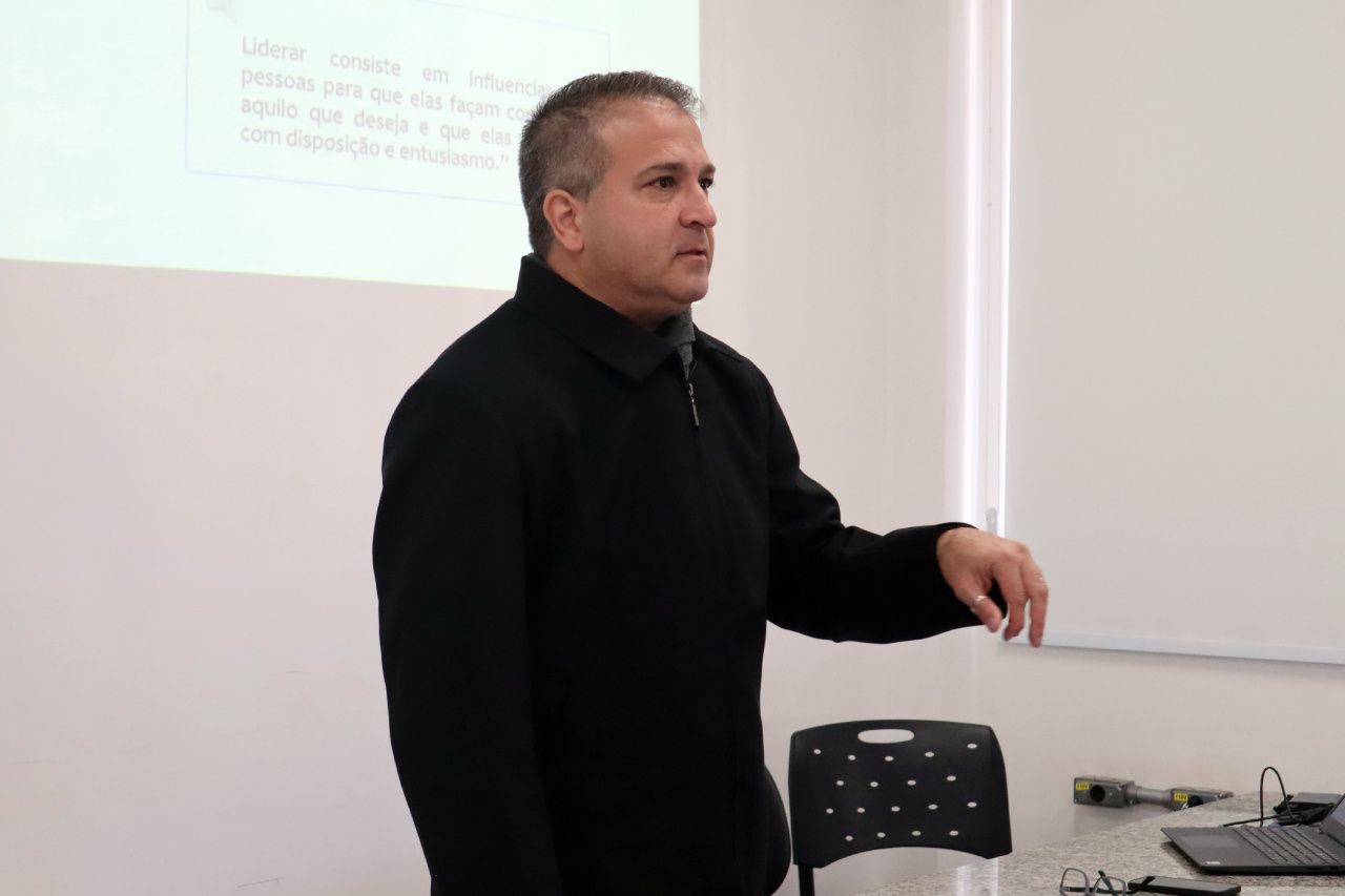 Um homem de jaqueta preta está parado em frente a um quadro branco