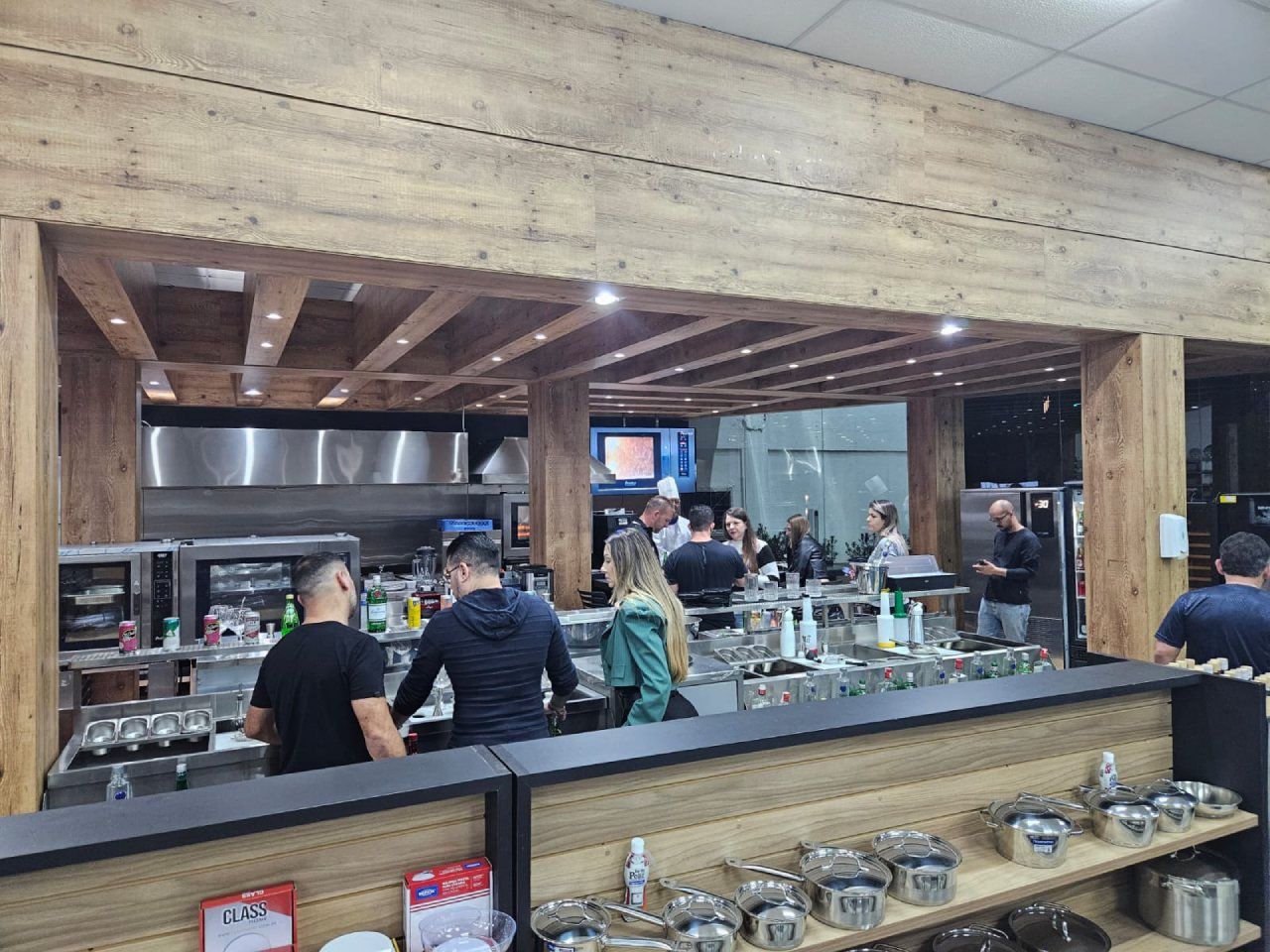 Um grupo de pessoas está em pé ao redor de um balcão em um restaurante.