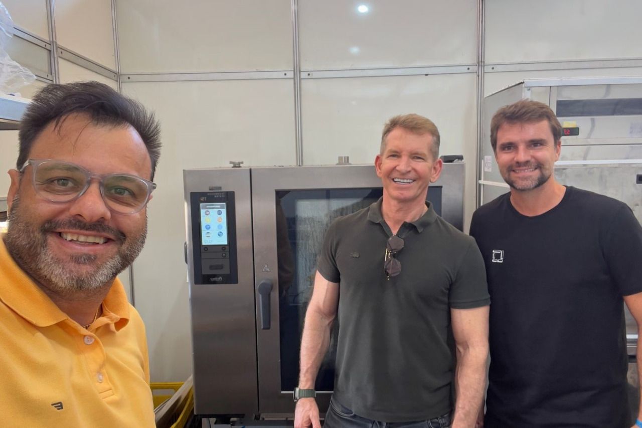 Três homens estão posando para uma foto em frente a um forno.