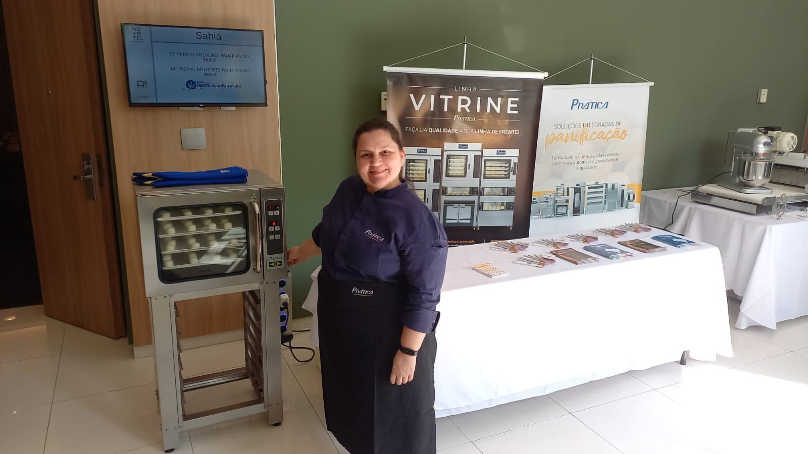 Uma mulher está parada em frente a uma mesa com uma placa que diz vitrine.