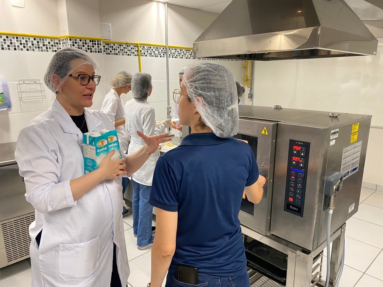 Um grupo de pessoas está em uma cozinha conversando entre si.