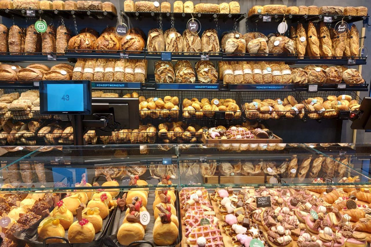 Uma vitrine de padaria cheia de pães e doces.