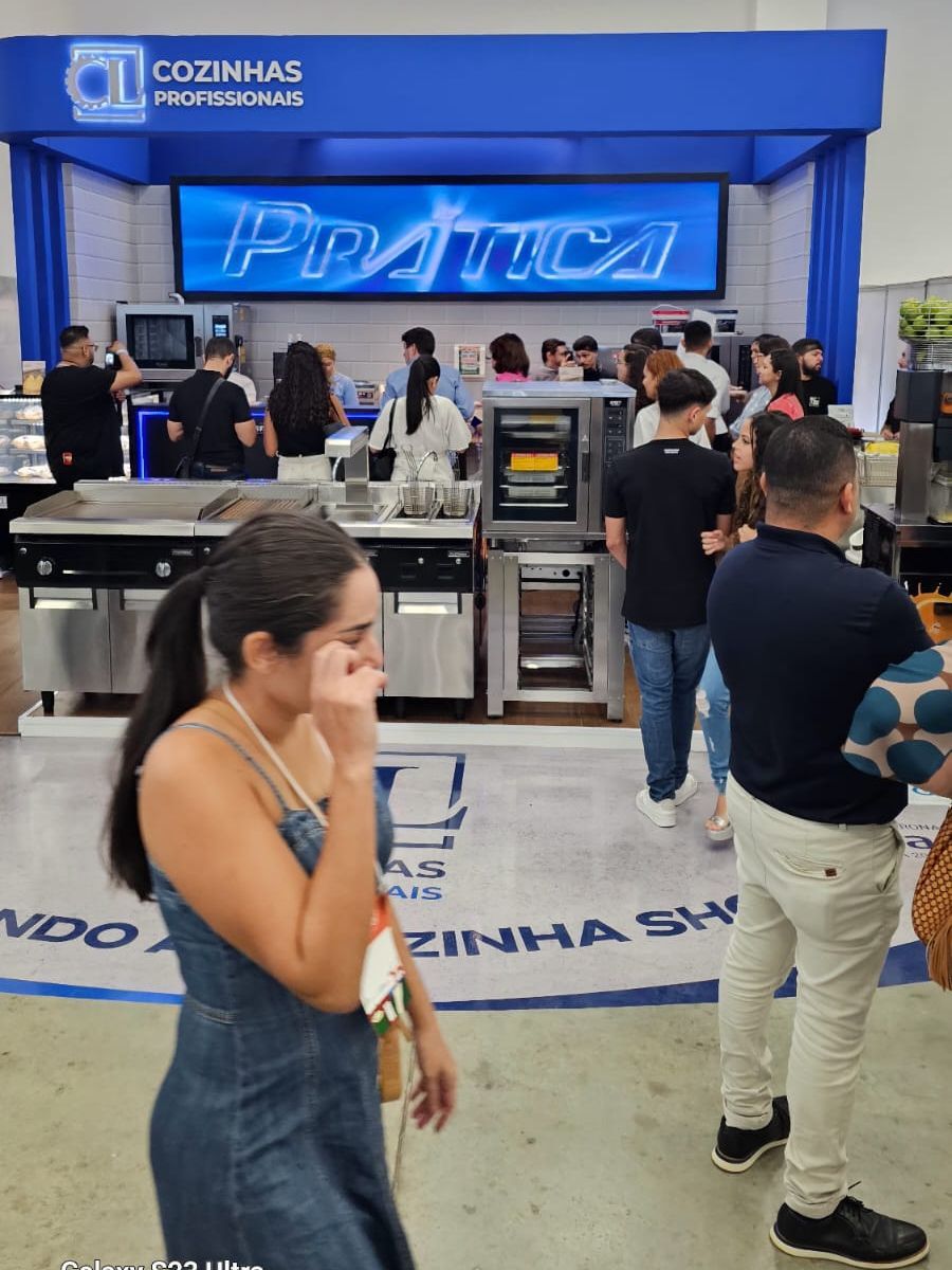 Um grupo de pessoas está em frente a uma placa que diz cozinhas