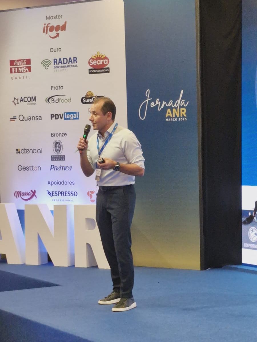 Um homem está em frente a uma grande placa que diz anr