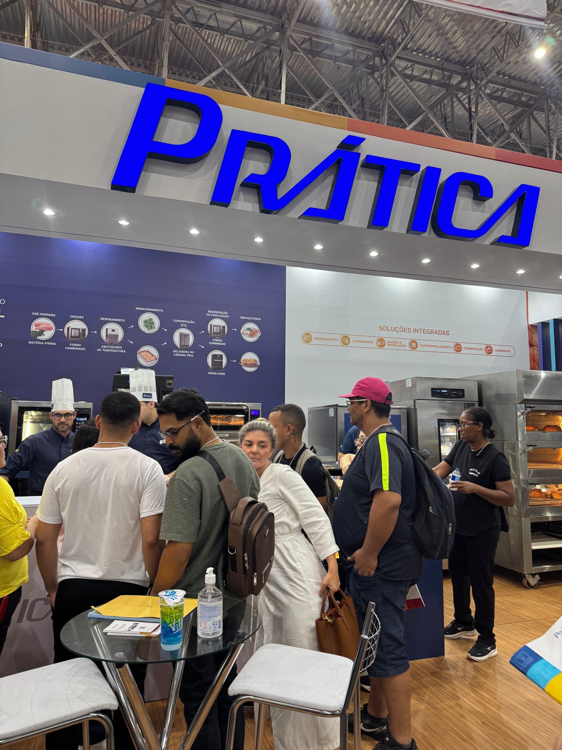 Pessoas em um estande de feira comercial com uma placa azul 