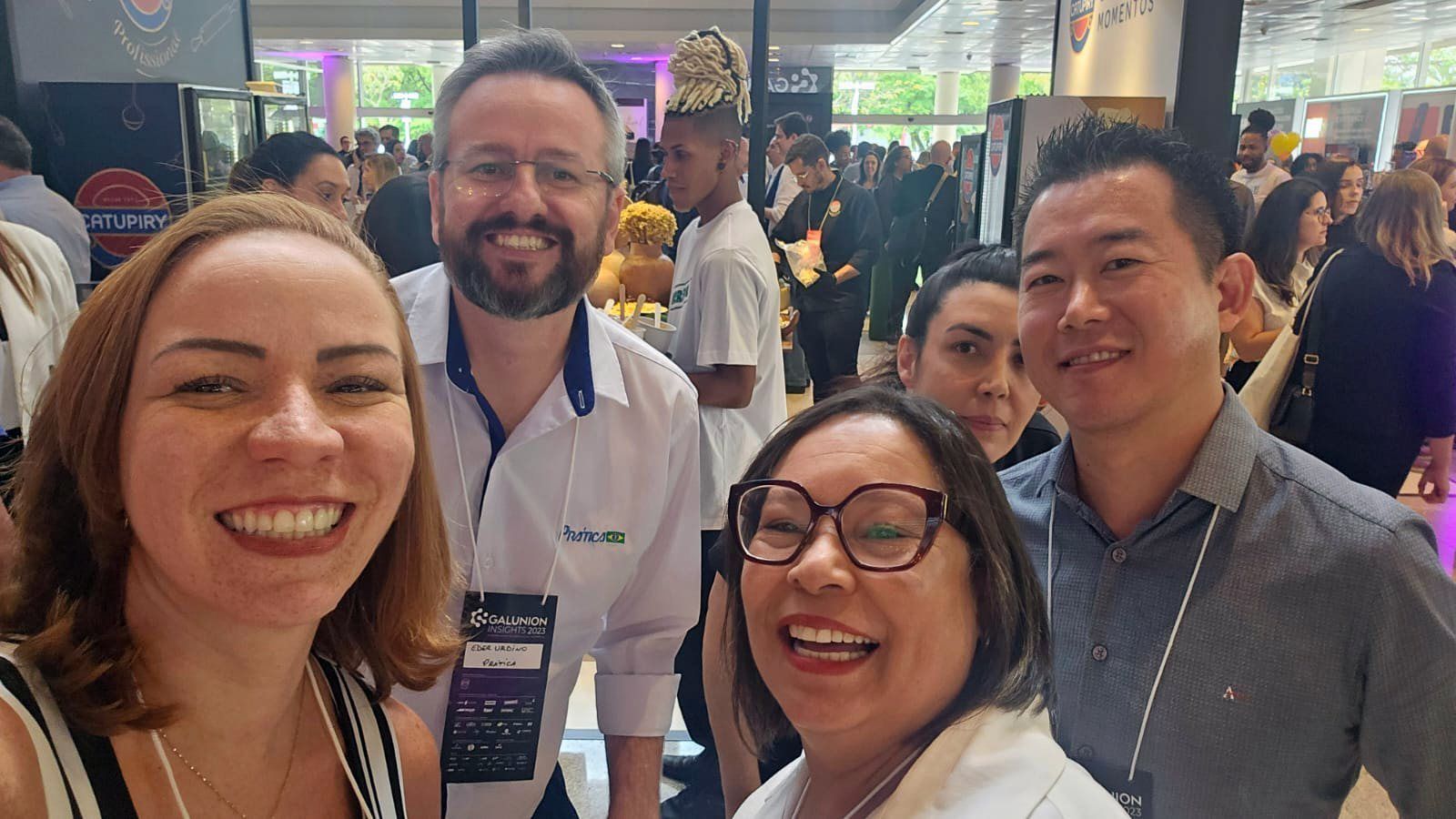 Um grupo de pessoas está posando para uma foto em uma sala lotada.