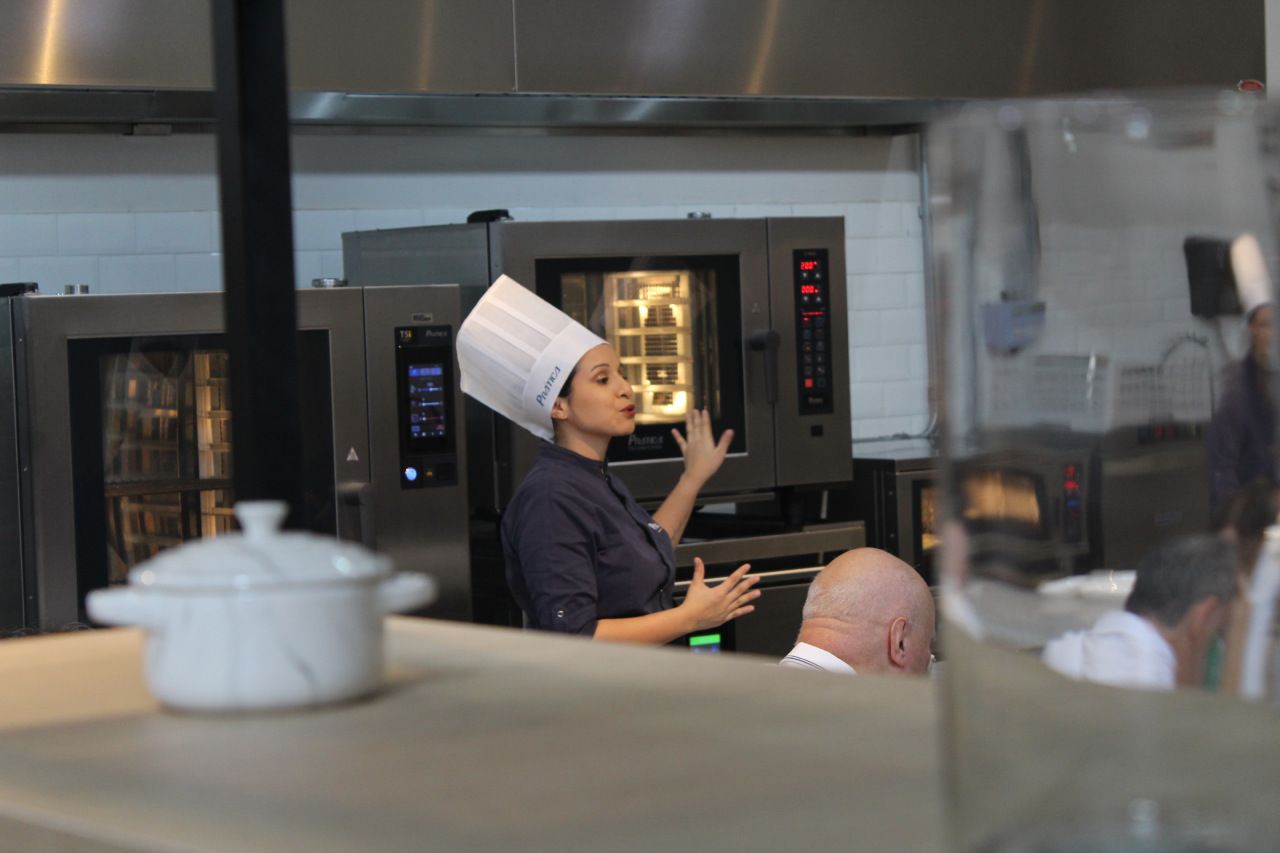 Uma mulher com chapéu de chef está parada na cozinha