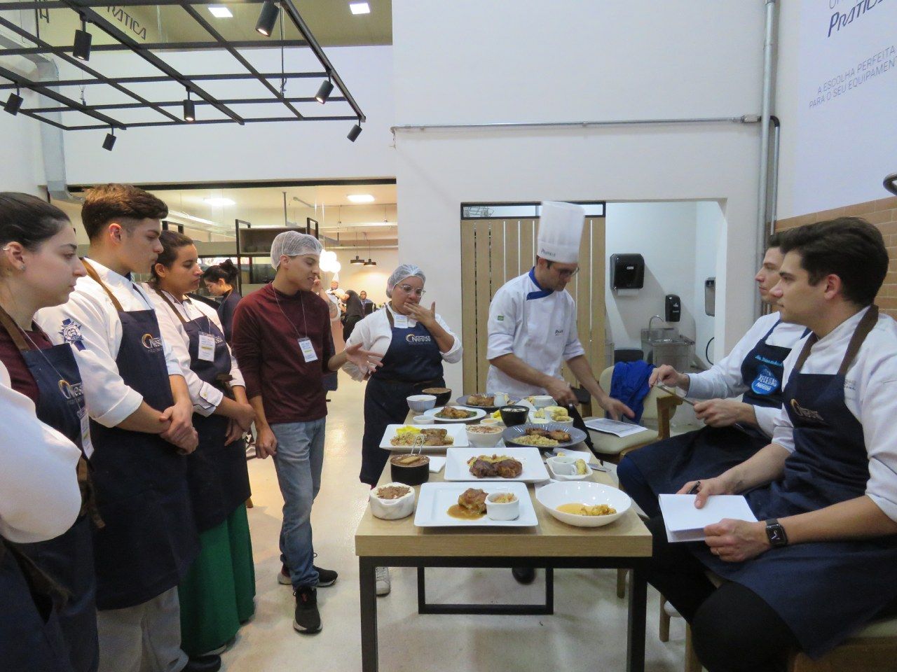 Um grupo de pessoas em pé ao redor de uma mesa com pratos de comida sobre ela