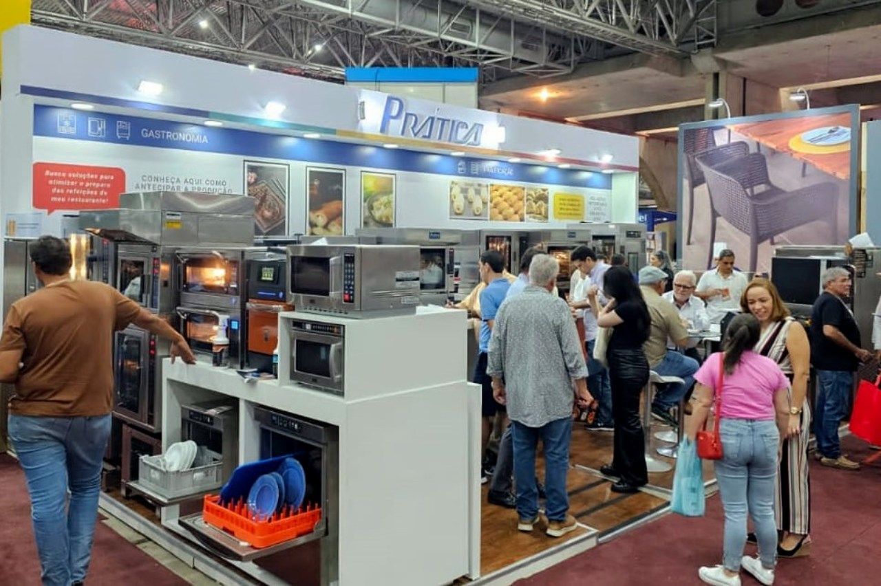 Um grupo de pessoas está em volta de um estande em uma convenção.