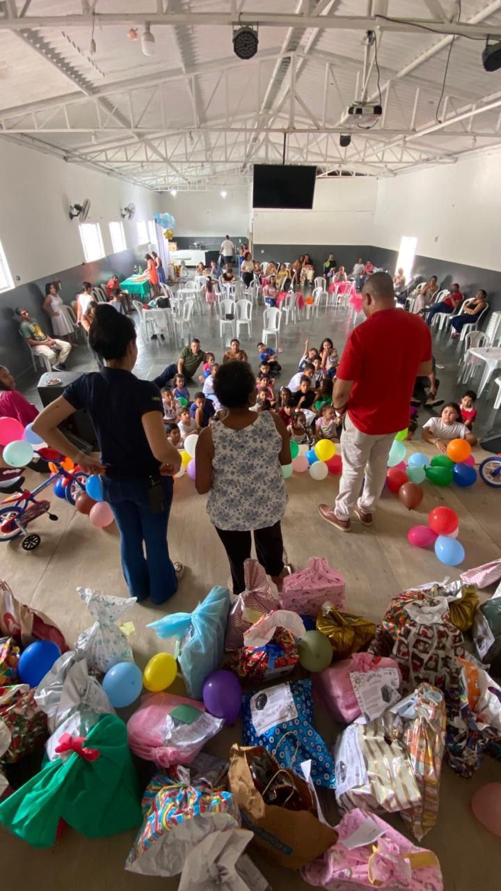 Um grupo de pessoas está em uma sala cheia de balões e presentes.