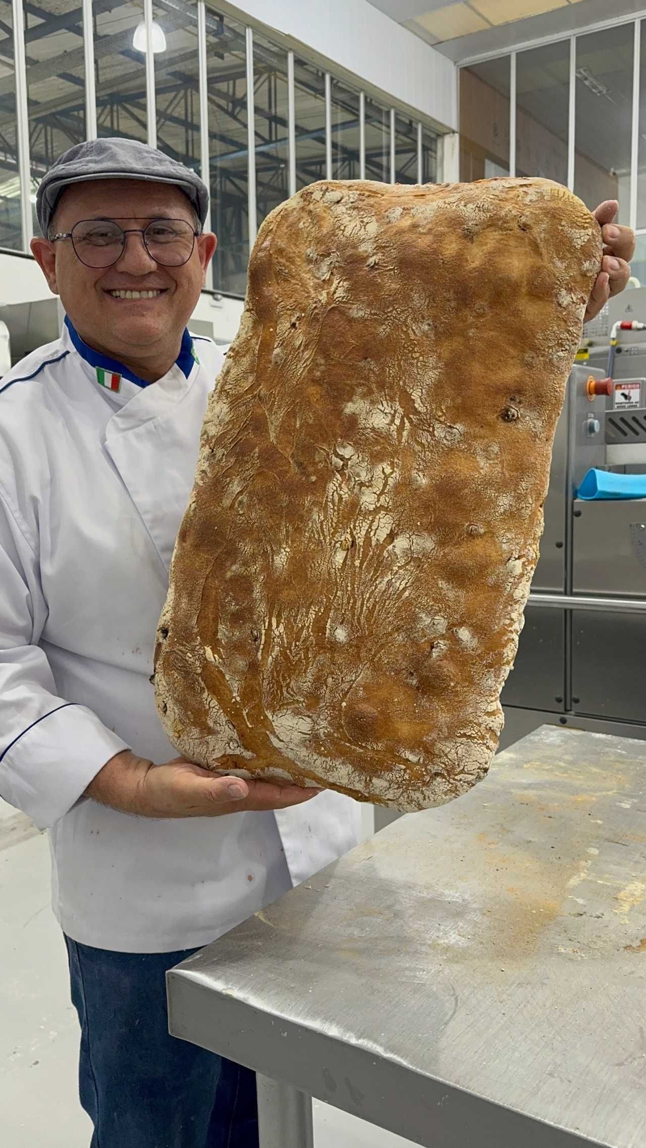 Um homem está segurando um grande pedaço de pão nas mãos.