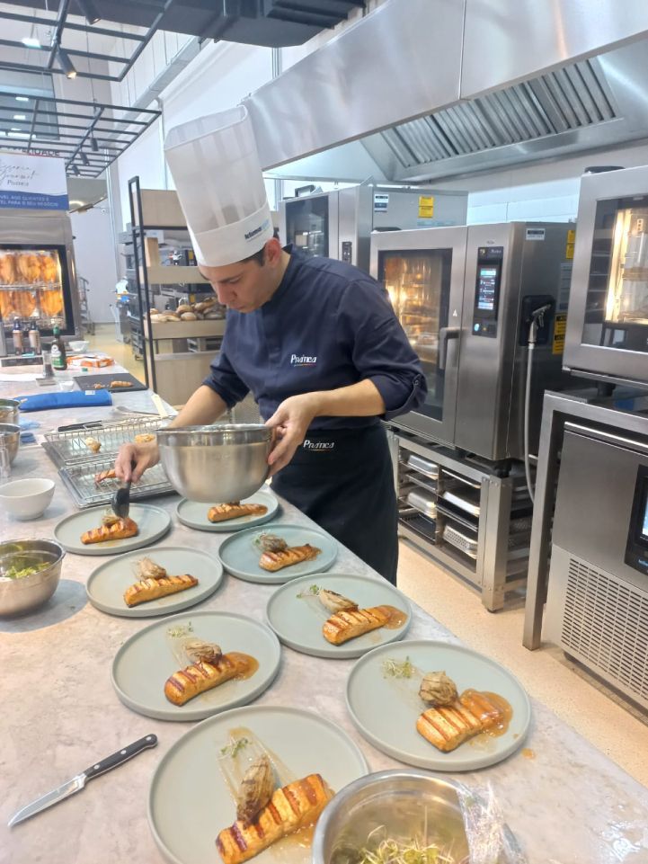 Um chef está preparando comida em pratos em uma cozinha.